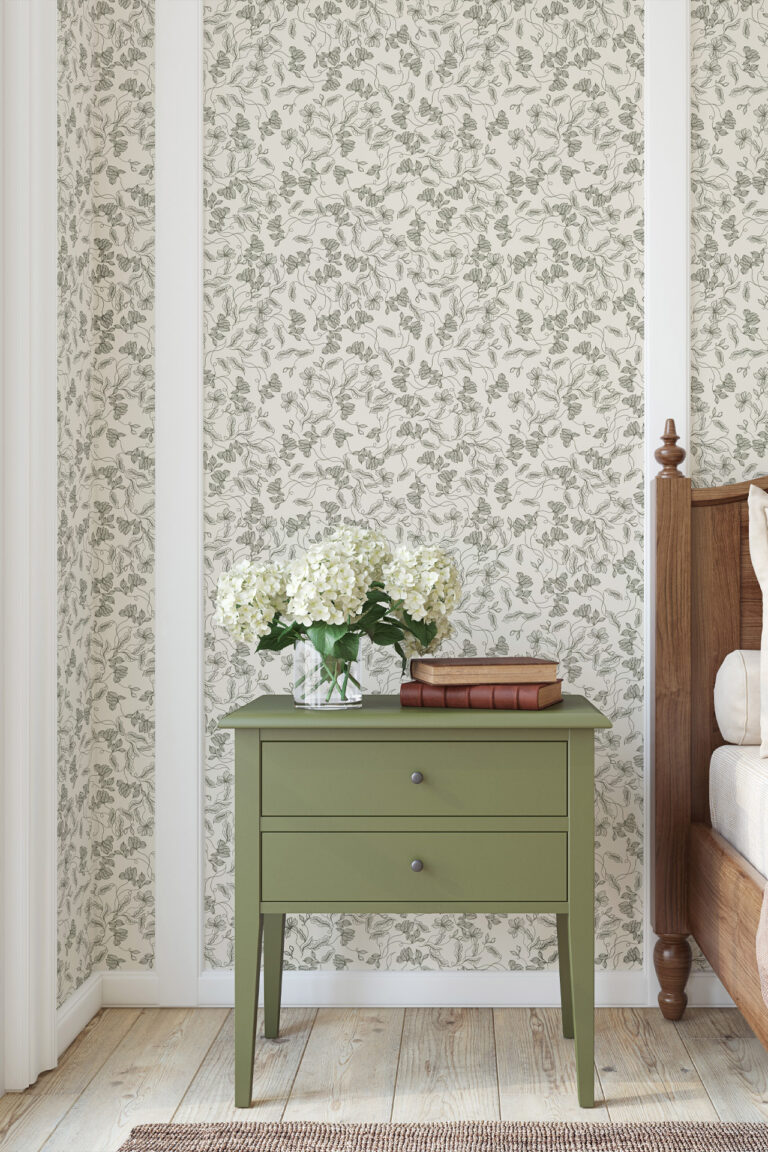 Elena Light Green floral Wallpaper used on wall in bedroom with the side of the bed in view and a green bedside table with 2 books on it and a vase of cream hydrangers - just one of our home decor inpsiration ideas