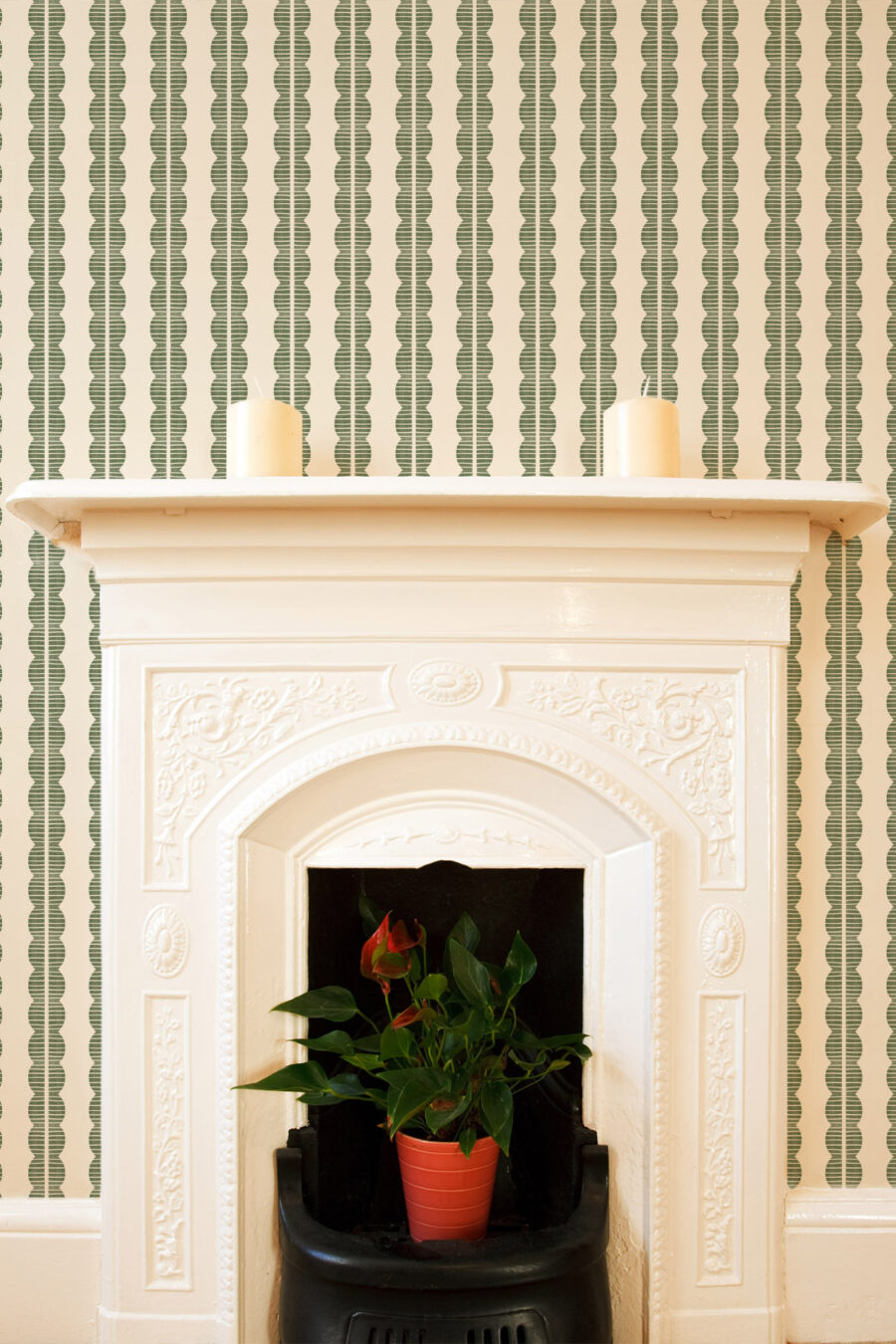 Rosalie Soft Green Wallpaper with cream background and olive green repeating abstract pattern surrounding a cream Fireplace. Mina is part of our home decor collection The Portrait Collection.